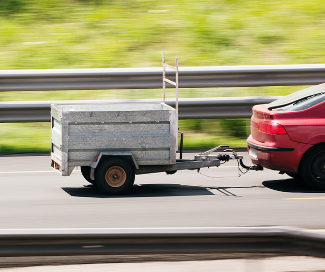 Carro vermelho a rebocar um atrelado em auto-estrada