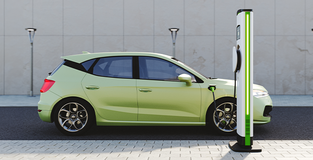 Carro elétrico verde num posto de carregamento num parque de estacionamento