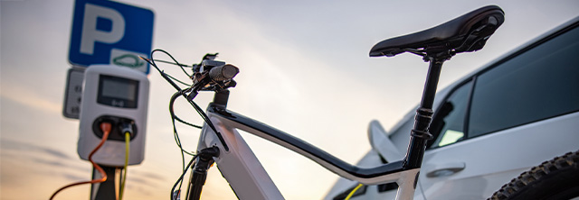 Bicicleta e automóvel elétrico em carregamento: ambos veículos de mobilidade elétrica